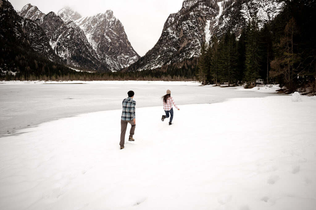 Couple running in snowy mountain landscape.