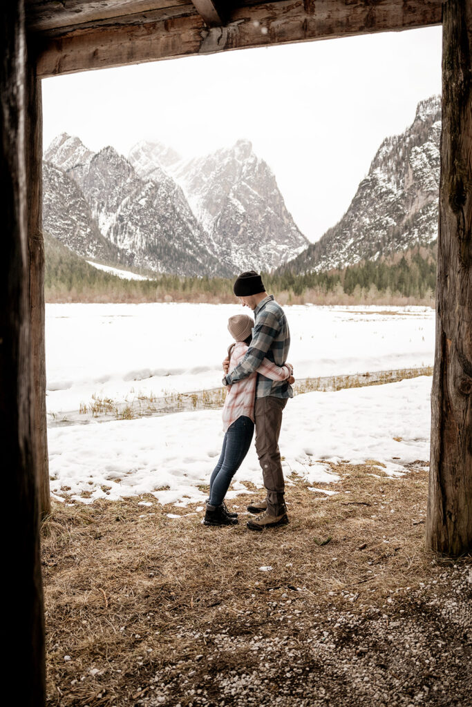 Couple hugging with snowy mountain backdrop.