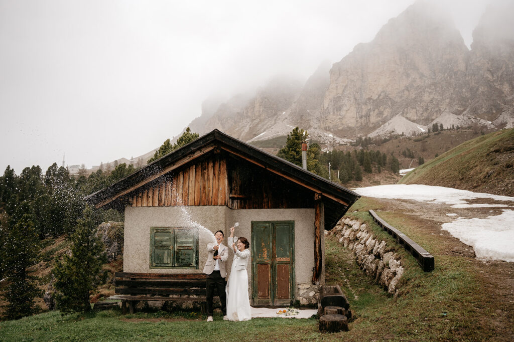 Couple celebrating with champagne outside rustic cabin