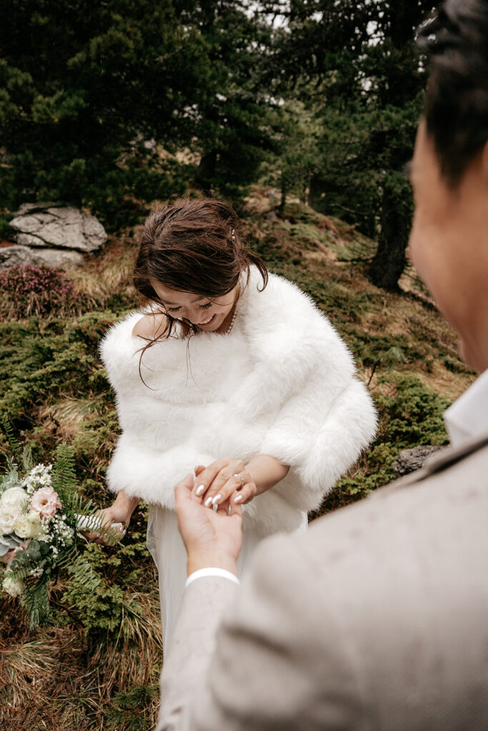 Bride holding groom's hand outdoors, wedding ceremony.