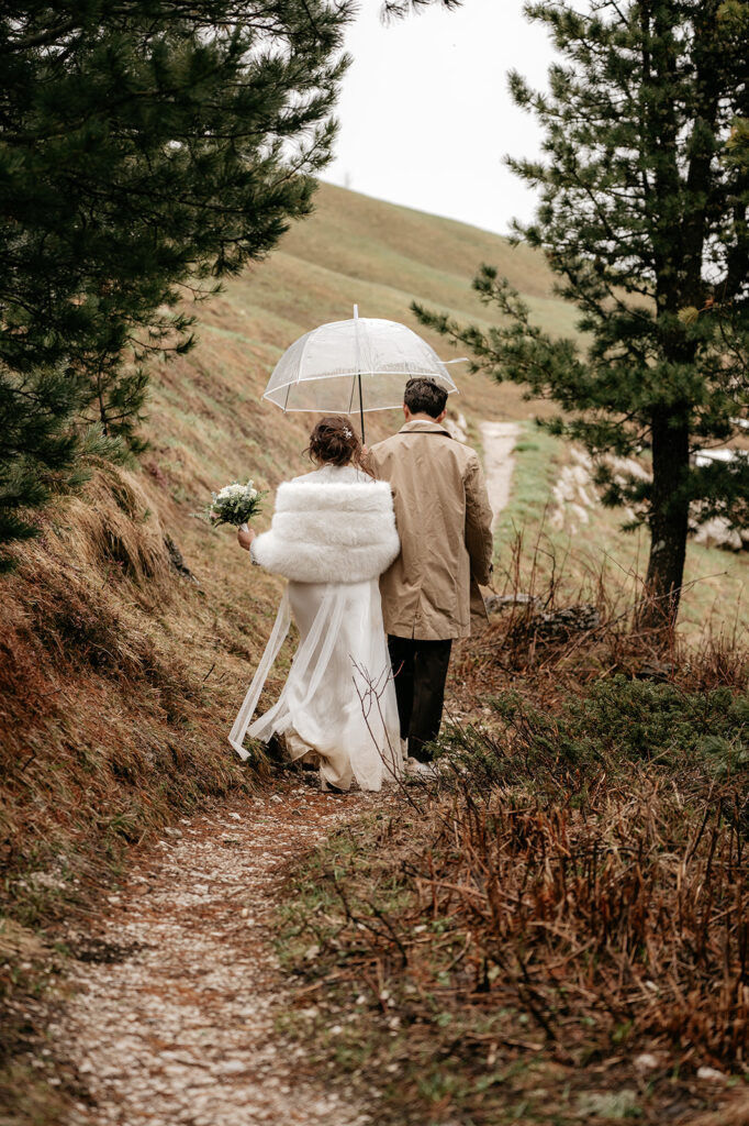 Couple walking under umbrella on forest path.