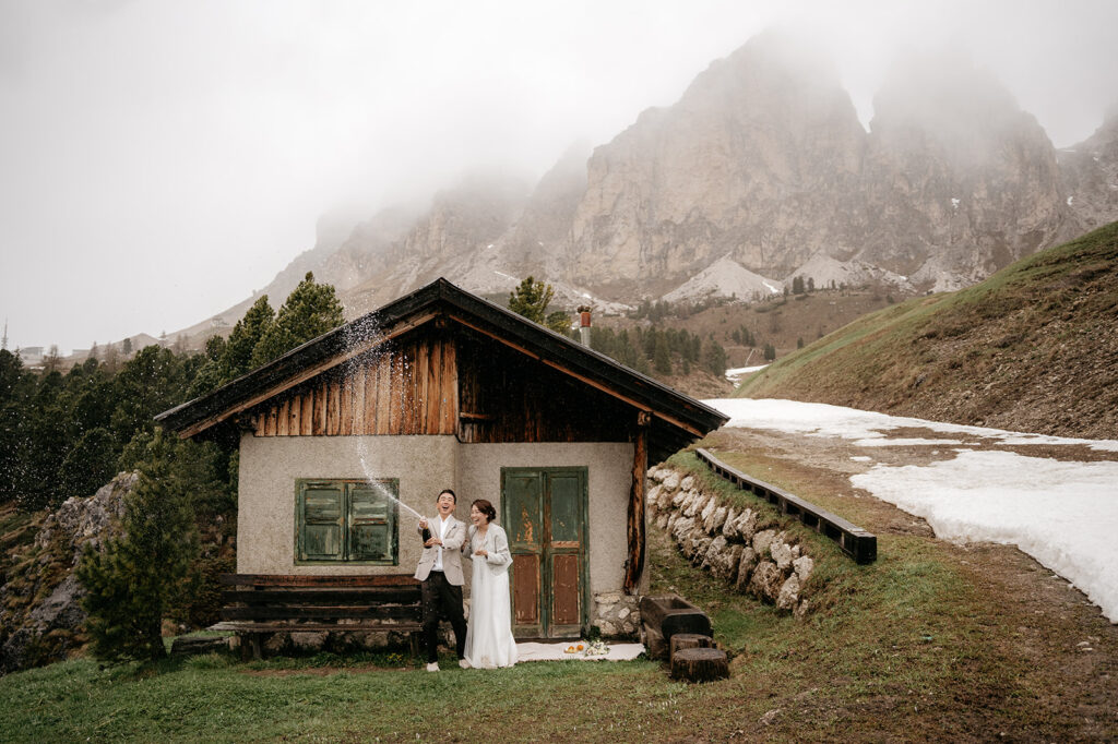 Couple celebrating outside mountain cabin with champagne.