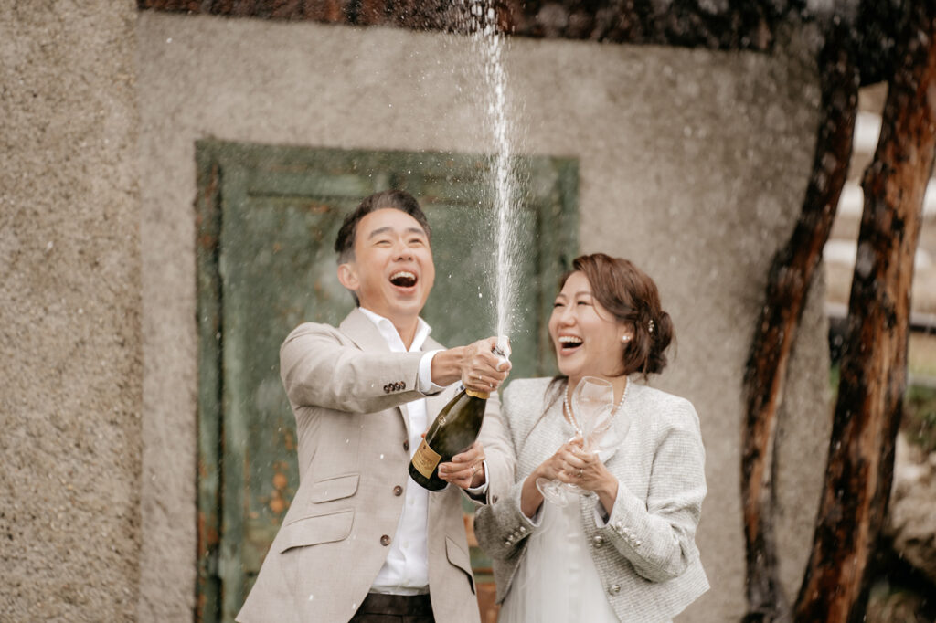 Couple celebrating with champagne outdoors.