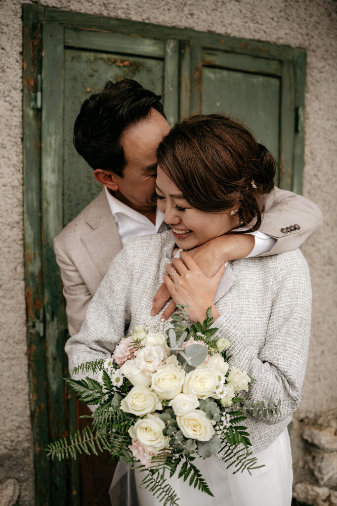 Smiling couple embracing with bouquet of flowers.