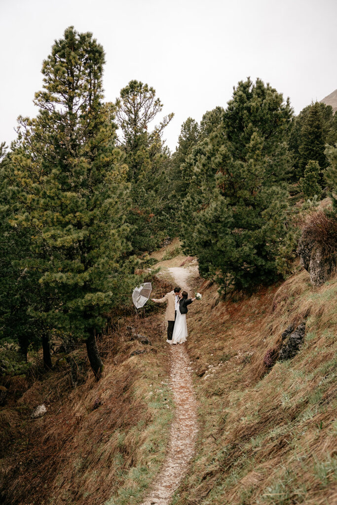 Wedding couple under umbrella on forest path