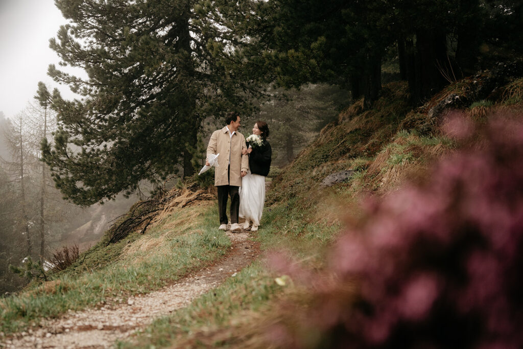 Couple walking on forest path with flowers.