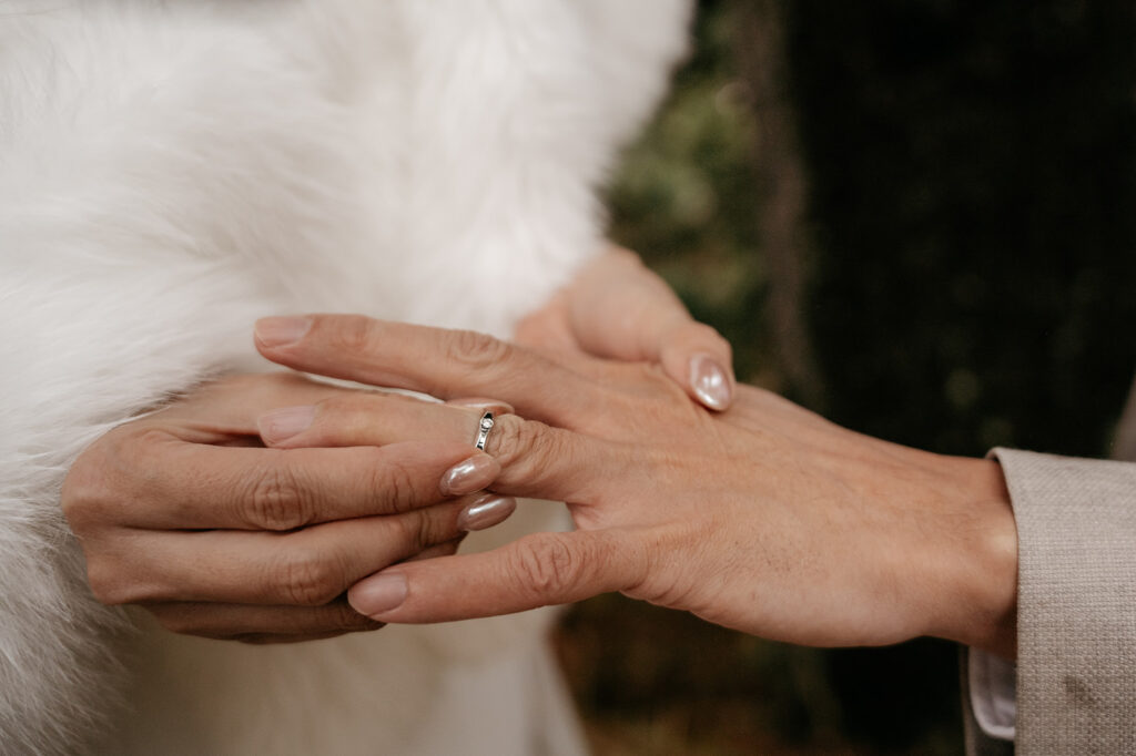 Couple exchanging wedding rings, close-up hands.