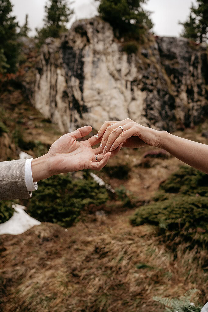 Close-up of couple holding hands outdoors.