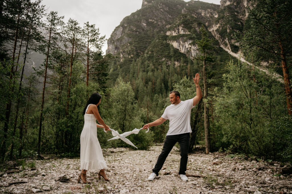 Couple playfully holding umbrellas in forest