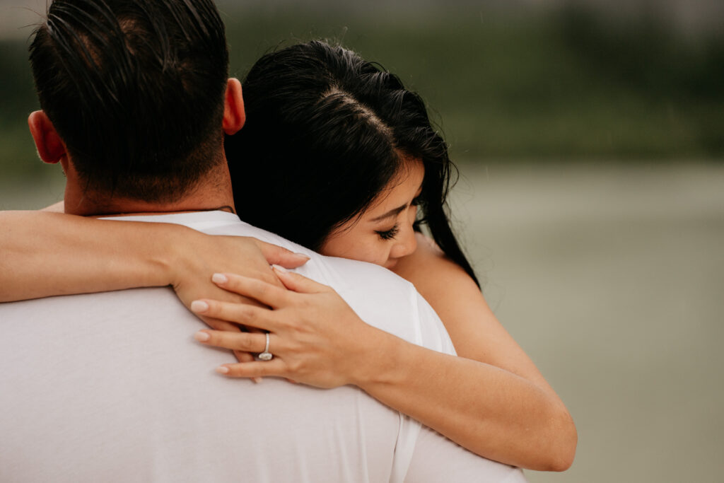 Woman hugs man, showing engagement ring.