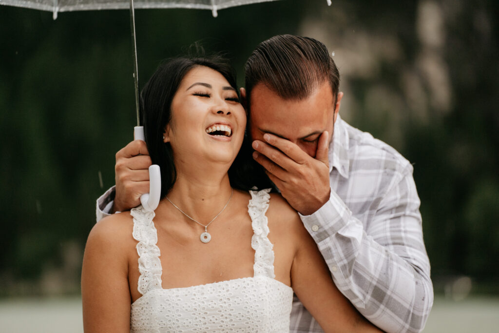 Couple laughing under transparent umbrella