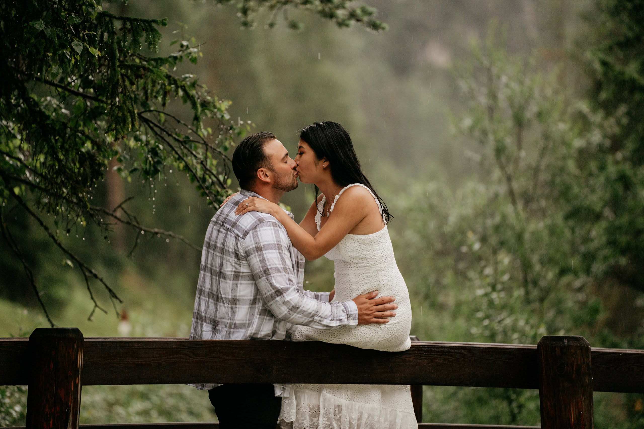 Couple kissing on a wooden bridge in nature.