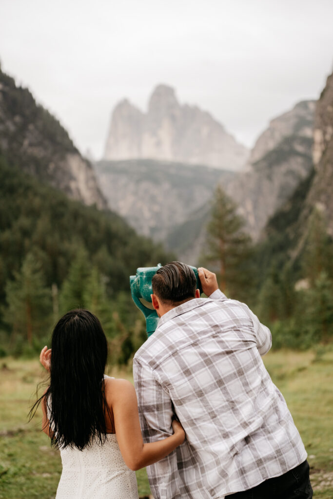 Couple admiring mountain view through telescope.