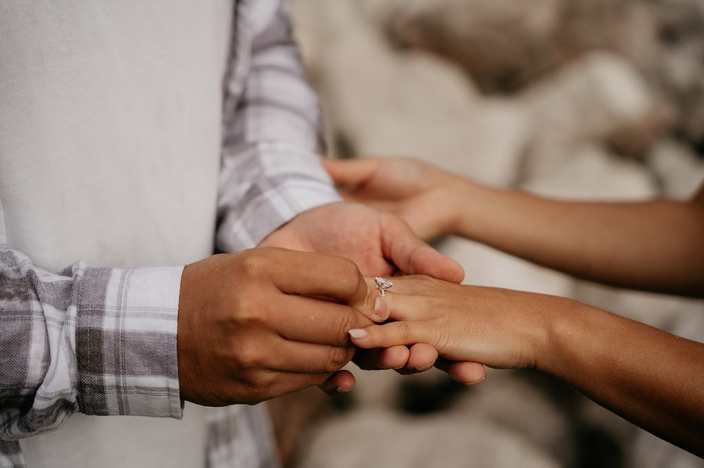 Man placing engagement ring on woman's finger