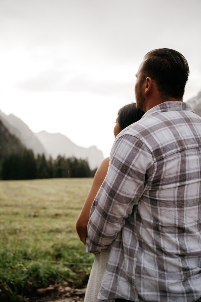 Couple embracing in a scenic mountain landscape.