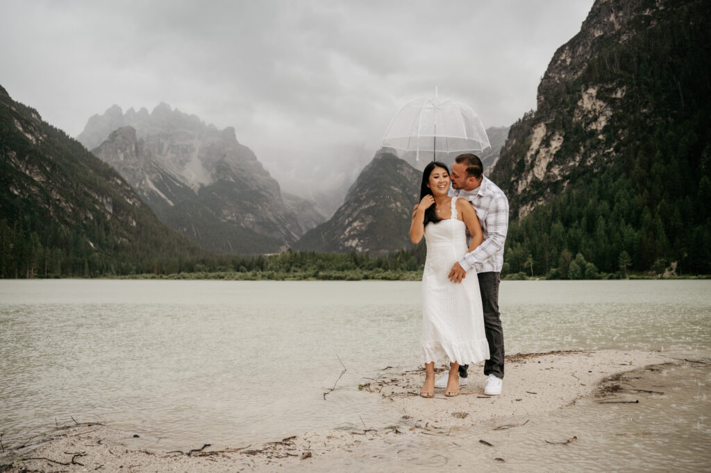 Couple hugging by a scenic mountain lake.