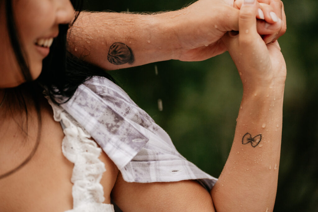 Close-up of couple holding hands, showing tattoos.