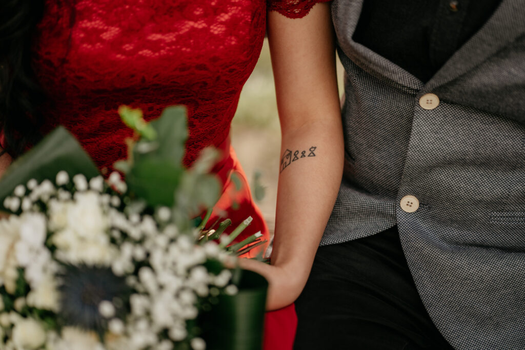 Couple with tattoo and bouquet in elegant clothes.