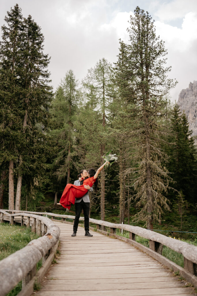 Couple on bridge in forest, man lifting woman.