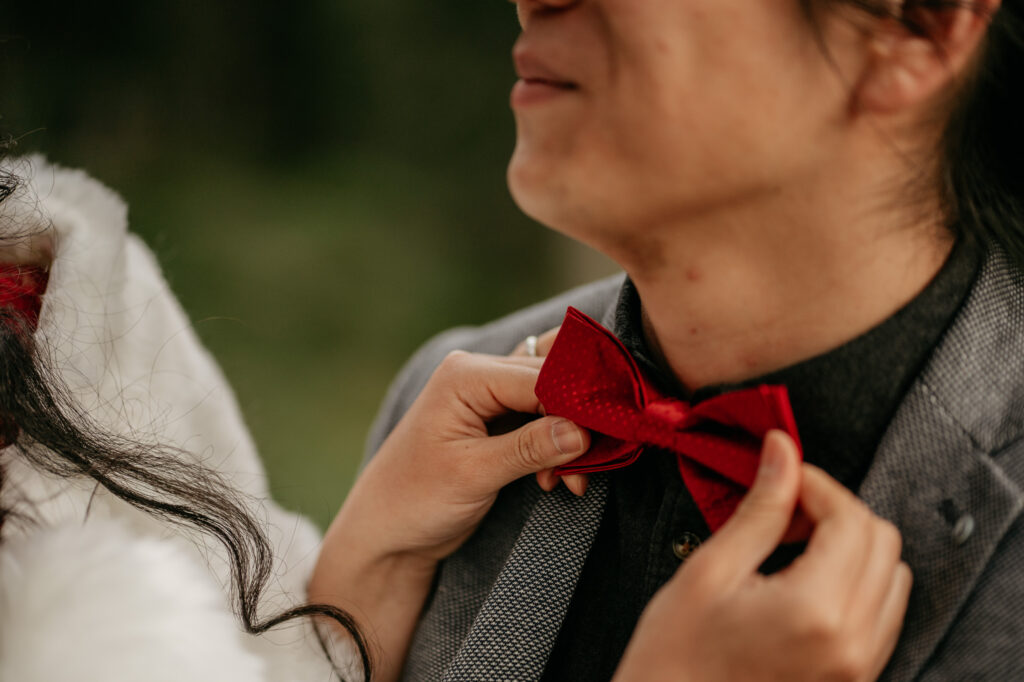 Adjusting a red bow tie on suit