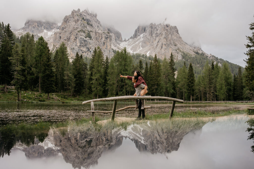 Couple on bridge, pointing at mountain scenery.