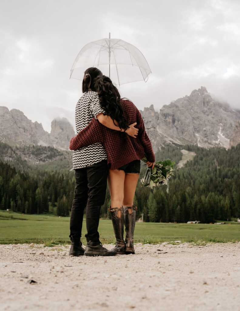 Couple hugging under umbrella in mountain scenery