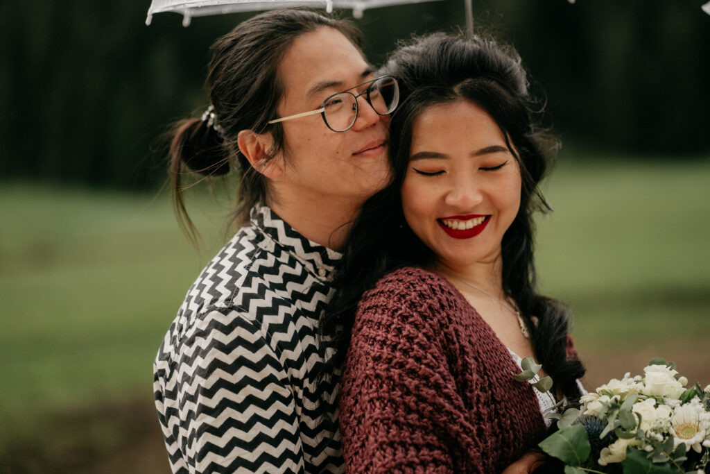 Smiling couple under umbrella with flowers