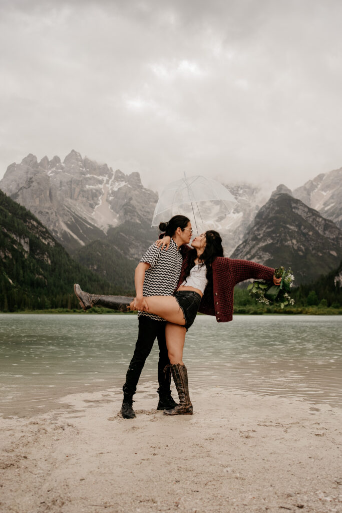 Couple embracing near lake with mountains background.