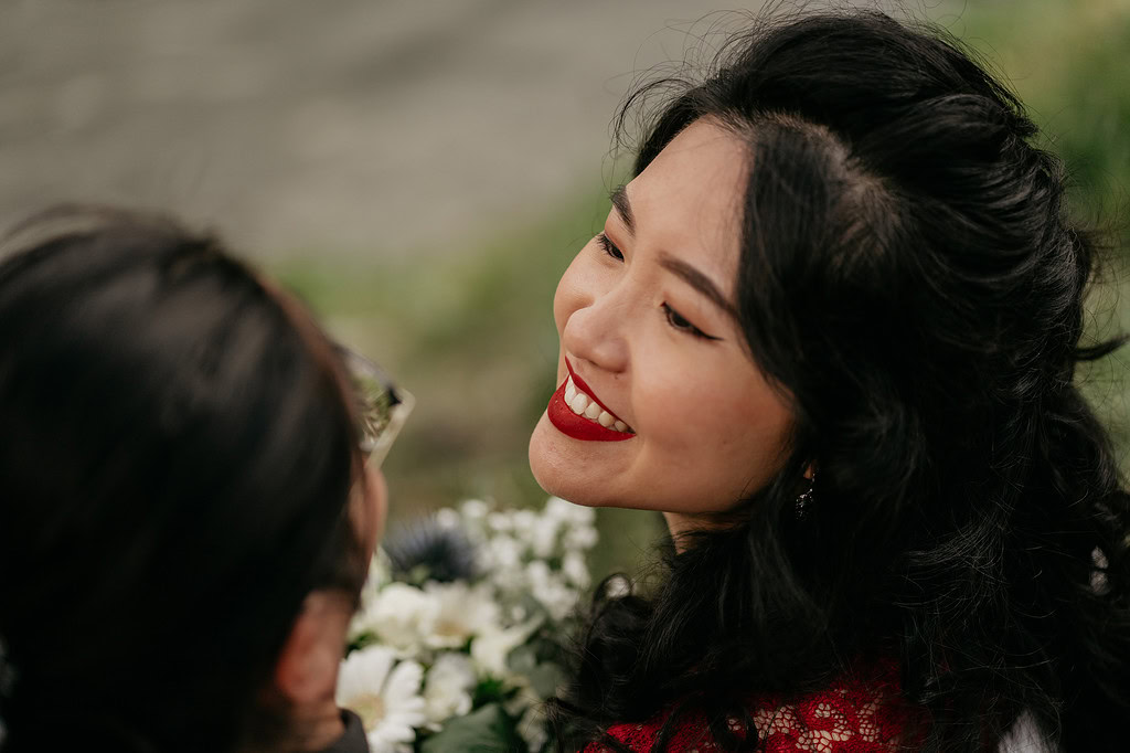 Smiling woman looking at another person with flowers.