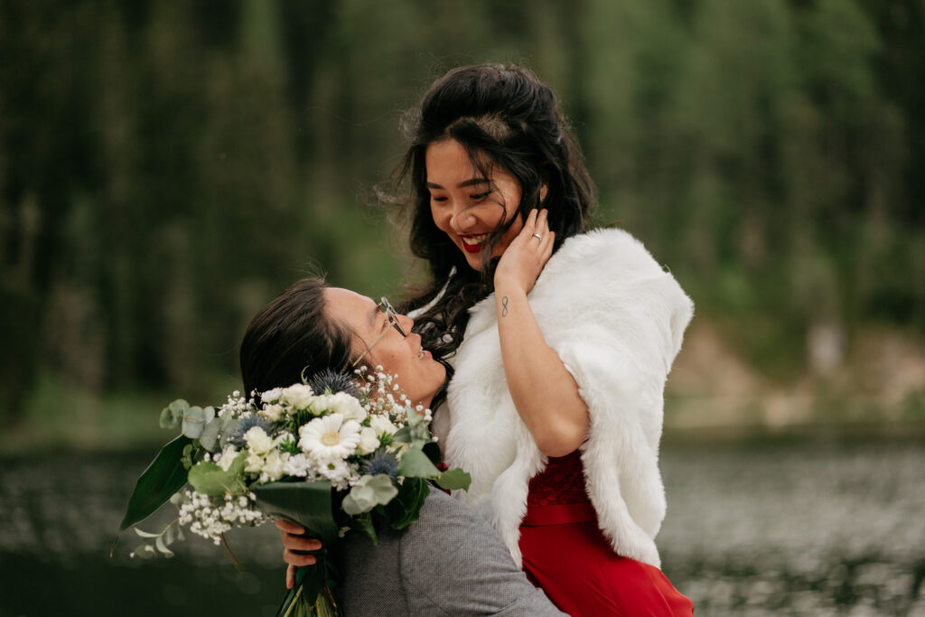 Couple embracing by a lake with flowers.