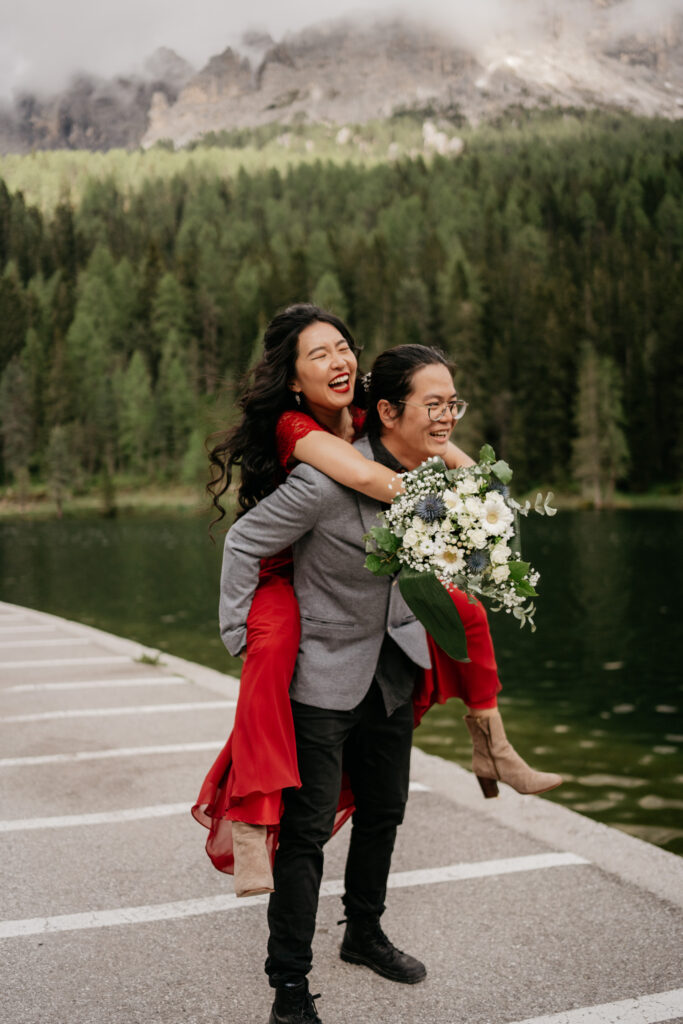 Couple enjoying piggyback ride by mountain lake.