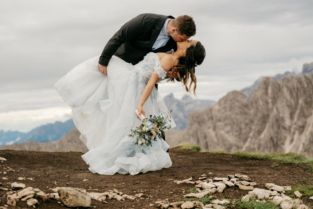 Wedding couple kissing on mountain top.