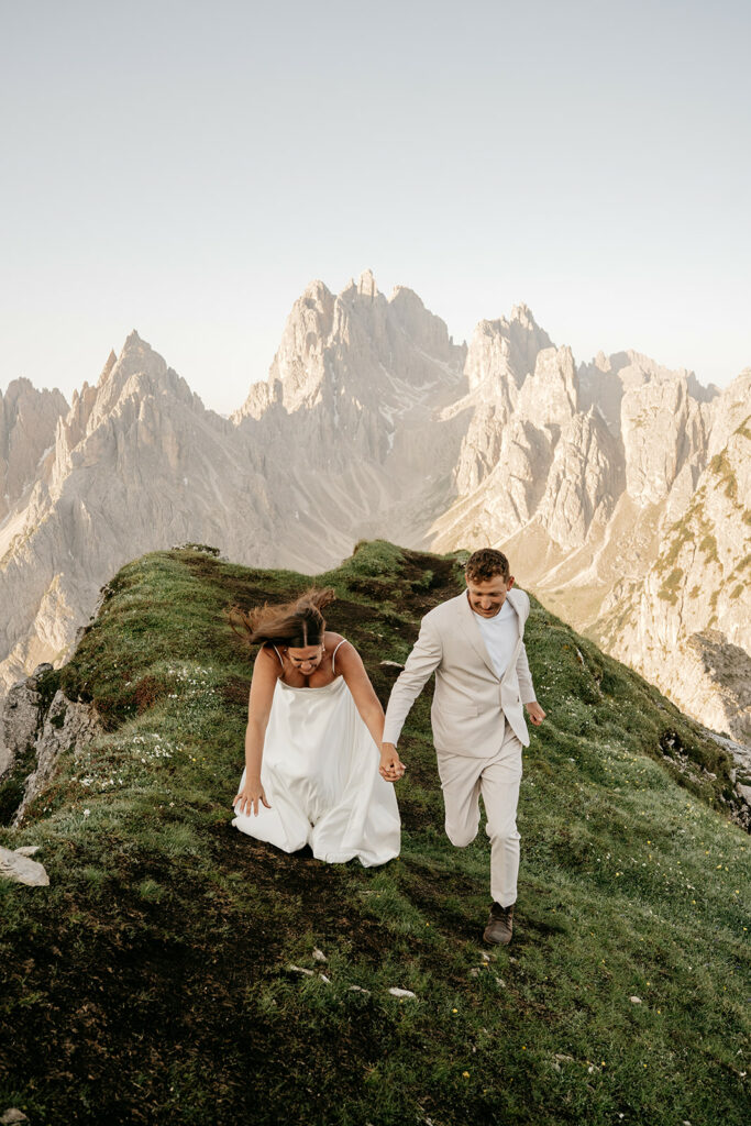 Couple hiking on mountain in wedding attire