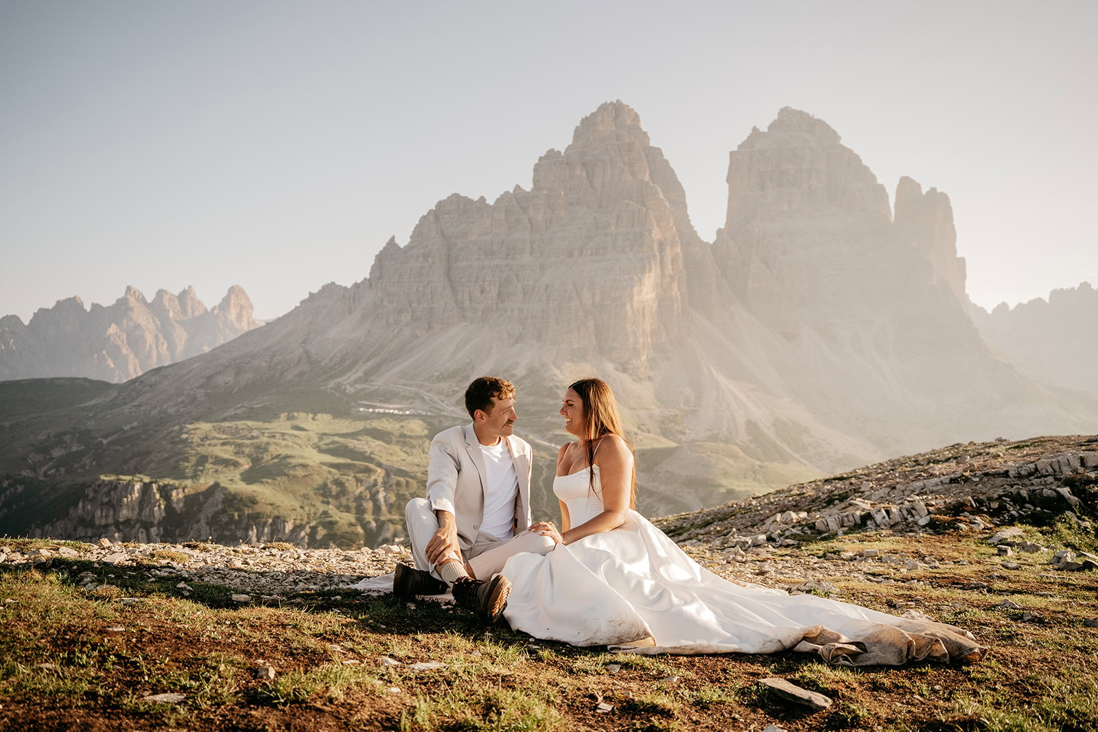 Bride and groom sit before majestic mountains.