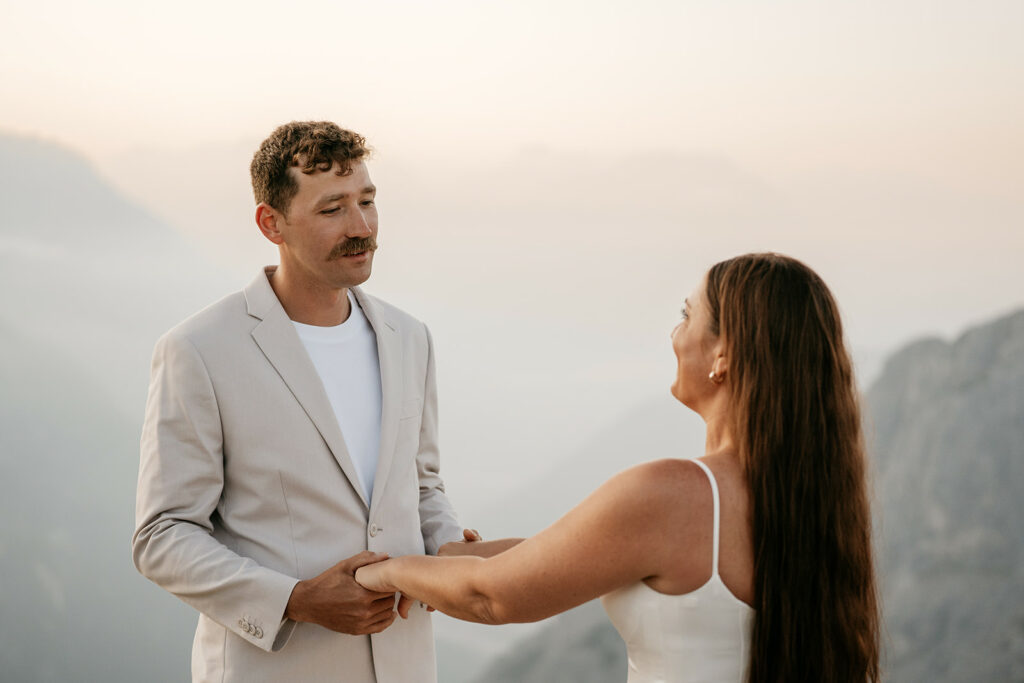 Couple holding hands on a mountaintop at sunset.