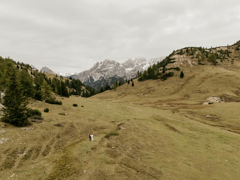 Couple walks through vast mountain valley landscape.