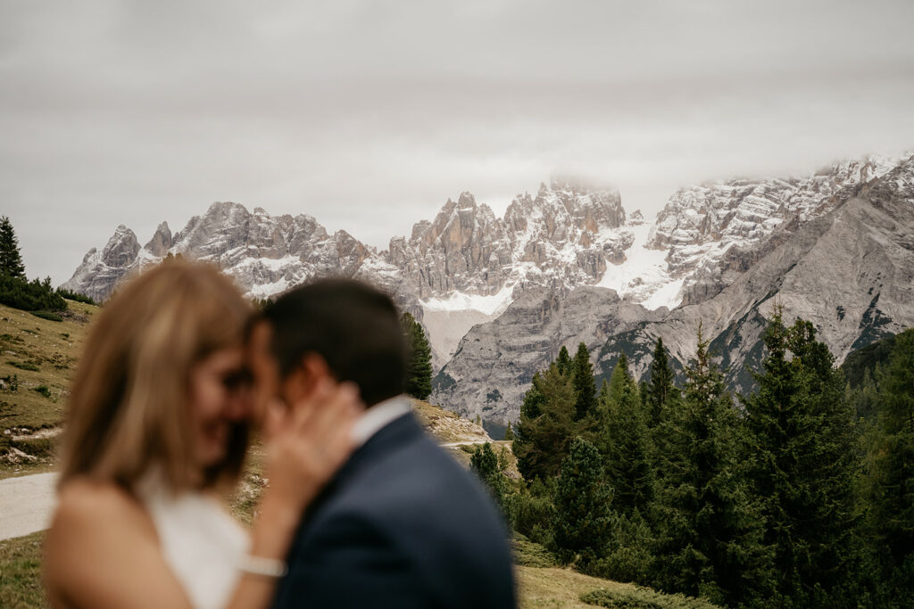Couple embracing with snowy mountains in background.