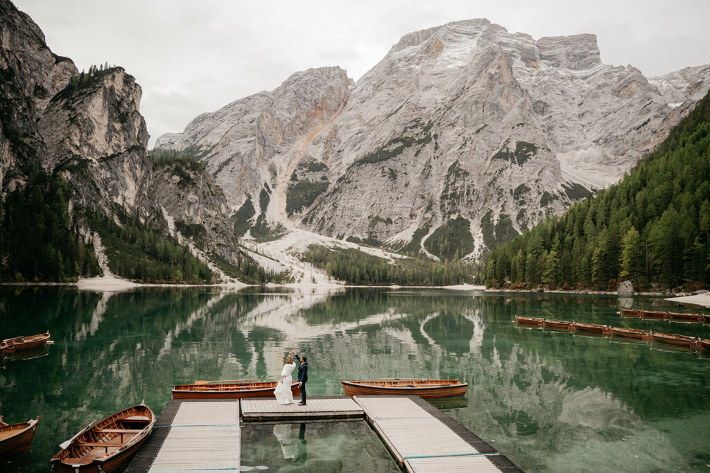 Couple on dock, surrounded by mountain lake scenery.