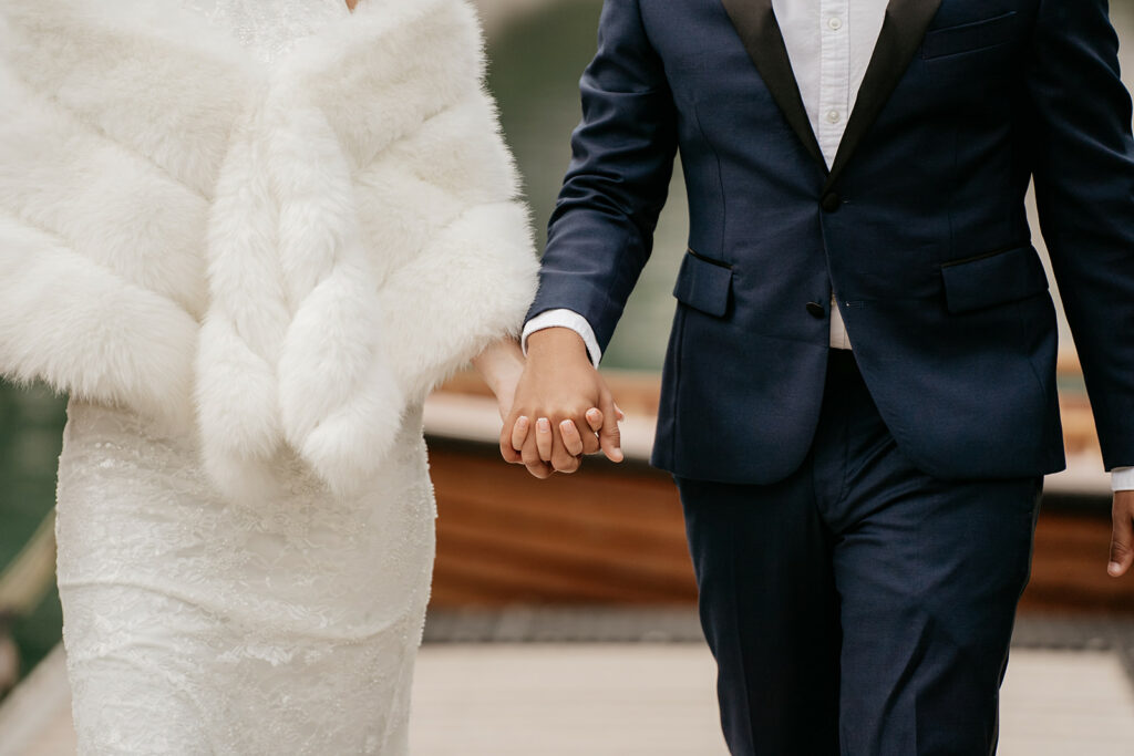 Bride and groom holding hands in formal attire.