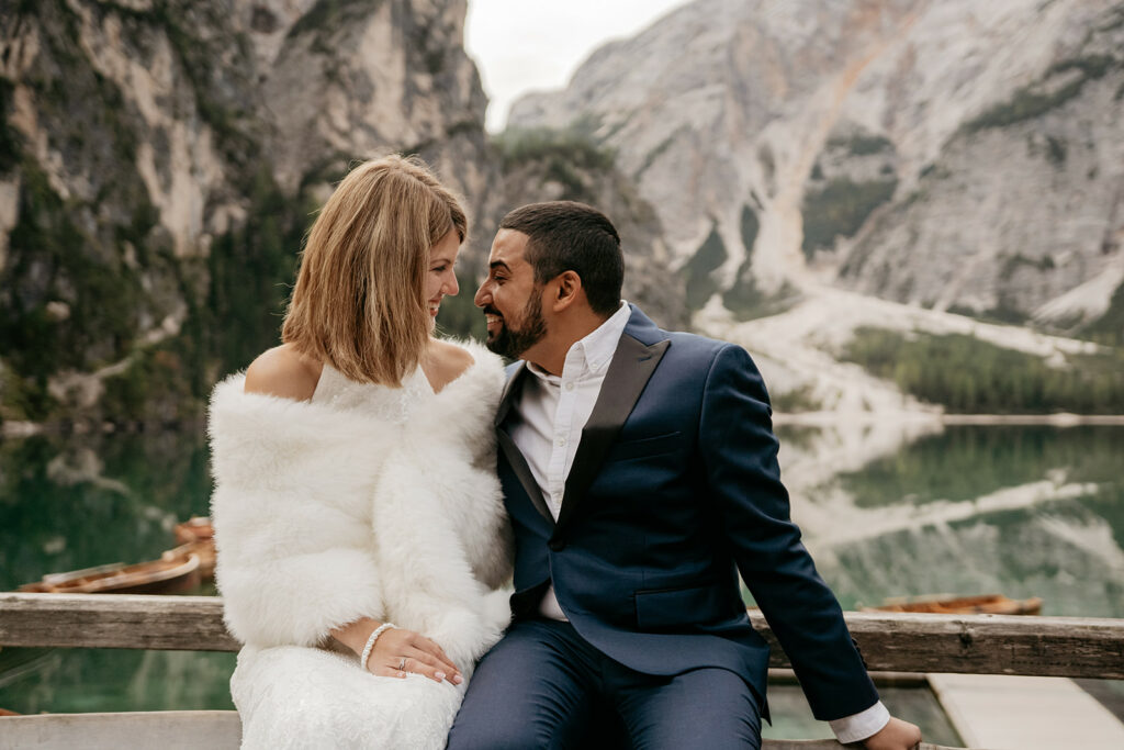 Couple in elegant attire, smiling in mountain setting.