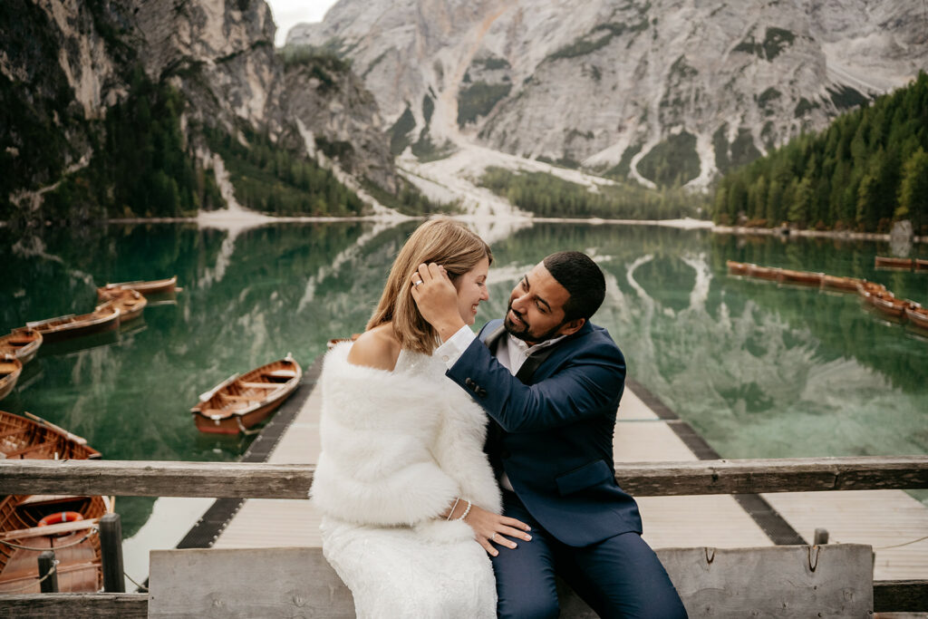 Couple embracing by a scenic lakeside pier.
