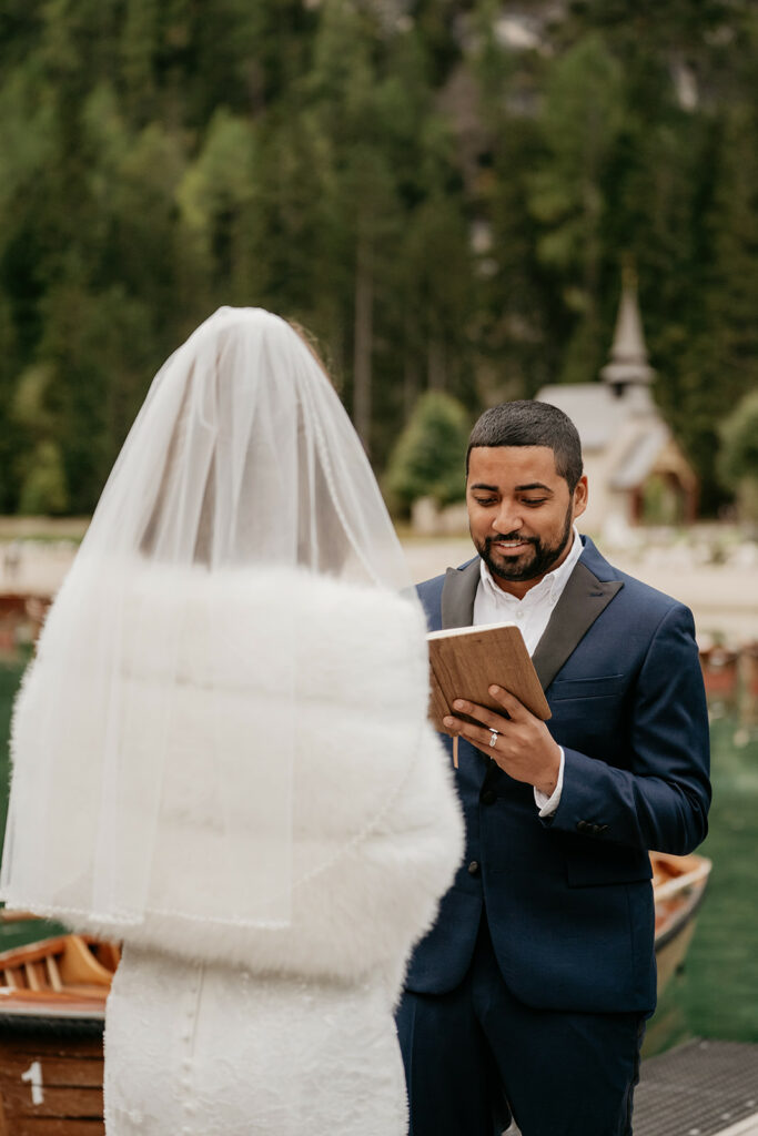 Groom reading vows to bride in outdoor wedding.