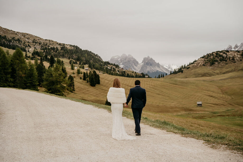 Couple walking on mountain path with scenic view.