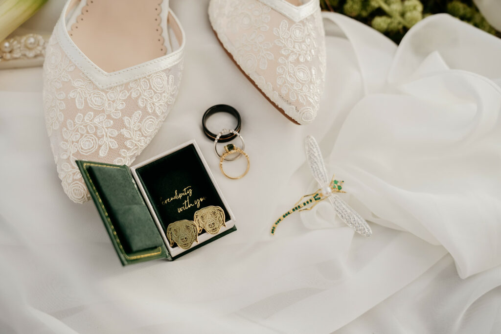 Wedding shoes, rings, cufflinks, dragonfly brooch on fabric.