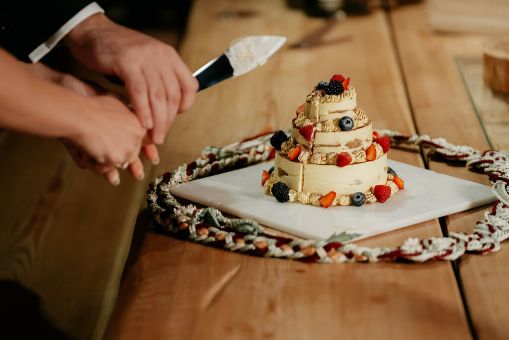 Couple cutting small tiered wedding cake.