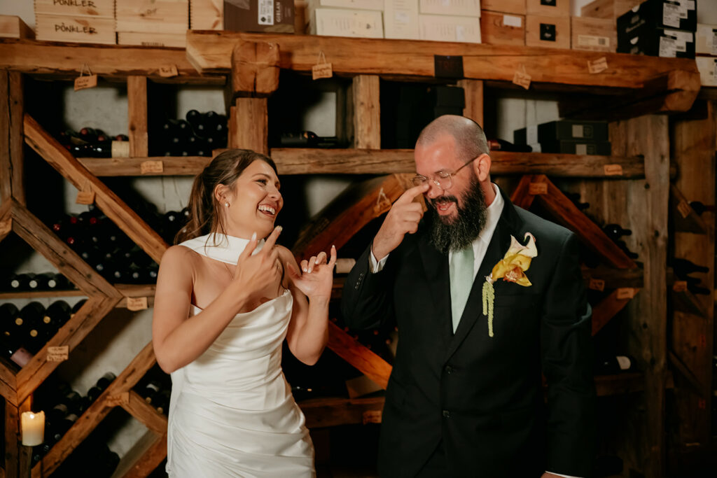 Couple laughing in wine cellar during wedding.