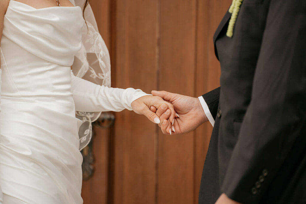 Bride and groom holding hands in wedding attire.