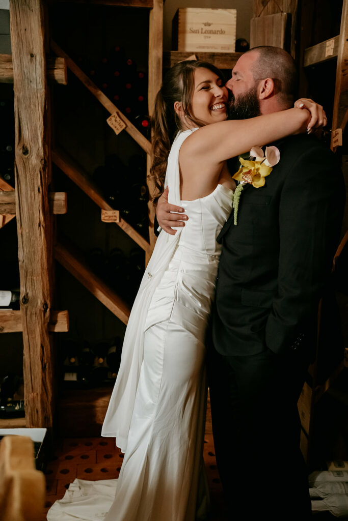 Smiling couple embracing in a wine cellar.
