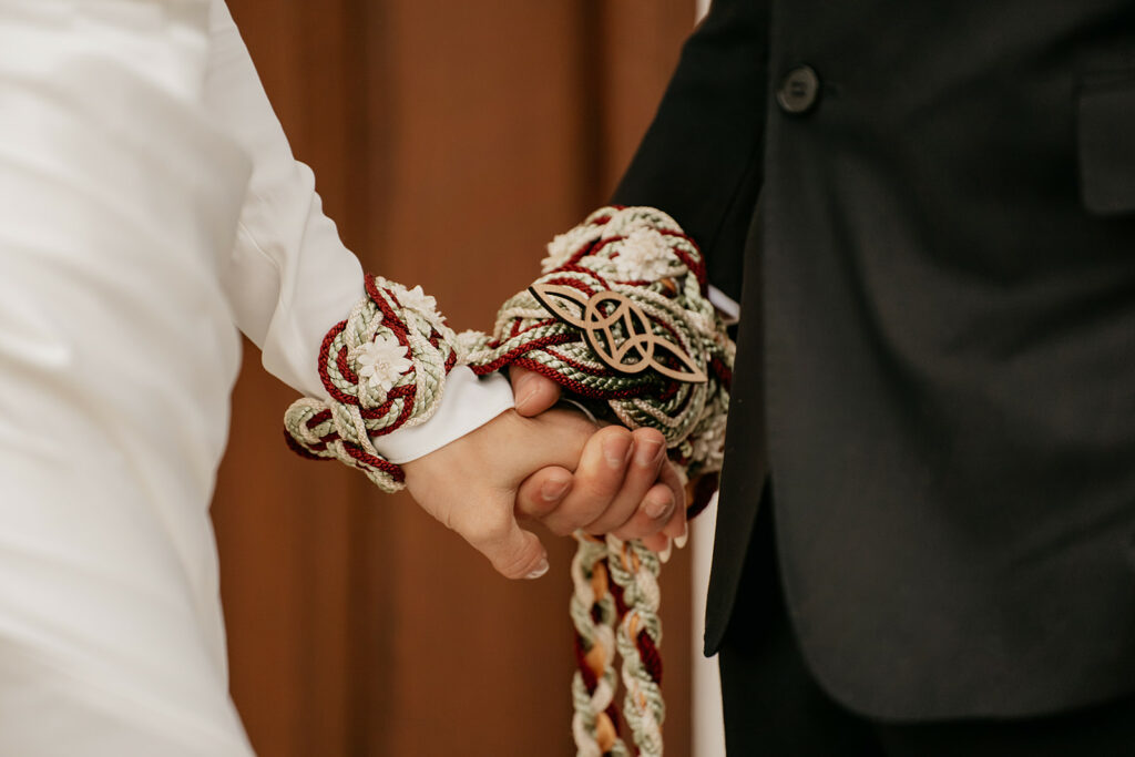 Closeup of hands tied in Celtic wedding ceremony.
