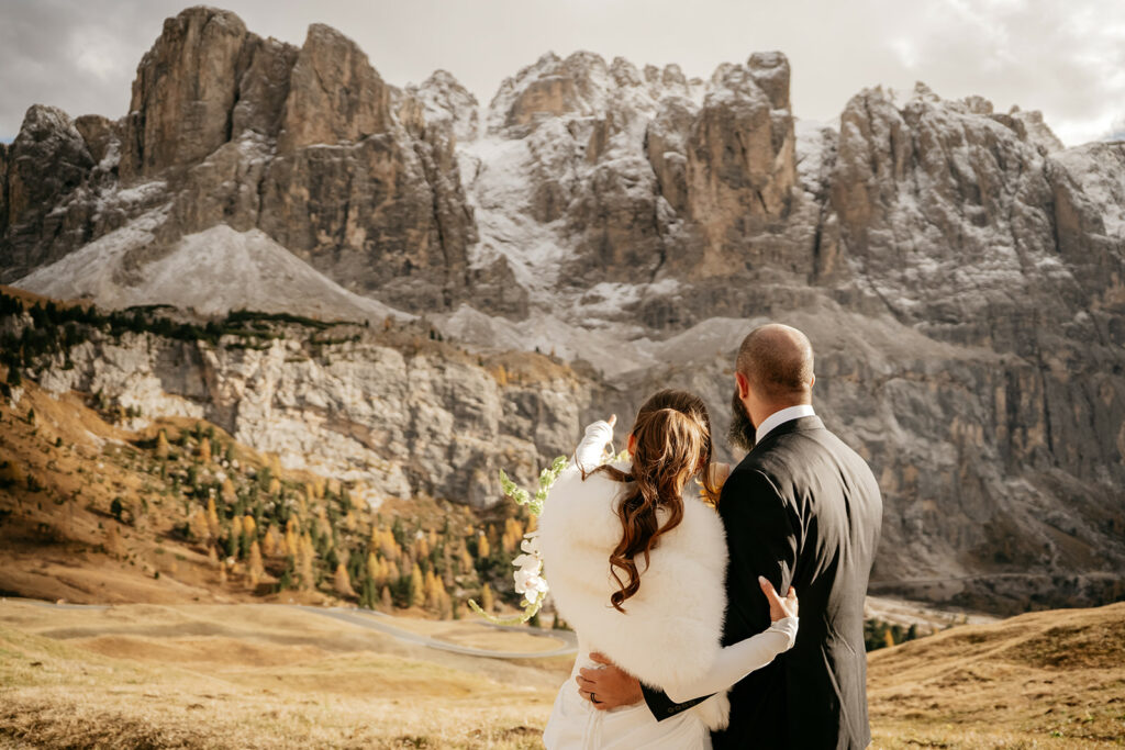 Couple embracing, overlooking majestic rocky mountains.